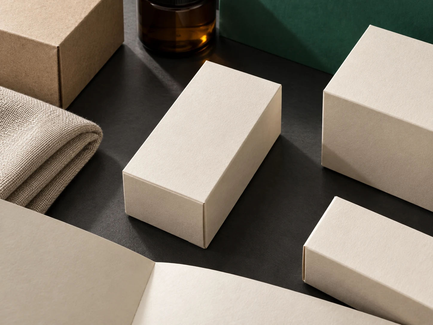 A considered arrangement of plain retail cartons, fabric and an amber jar